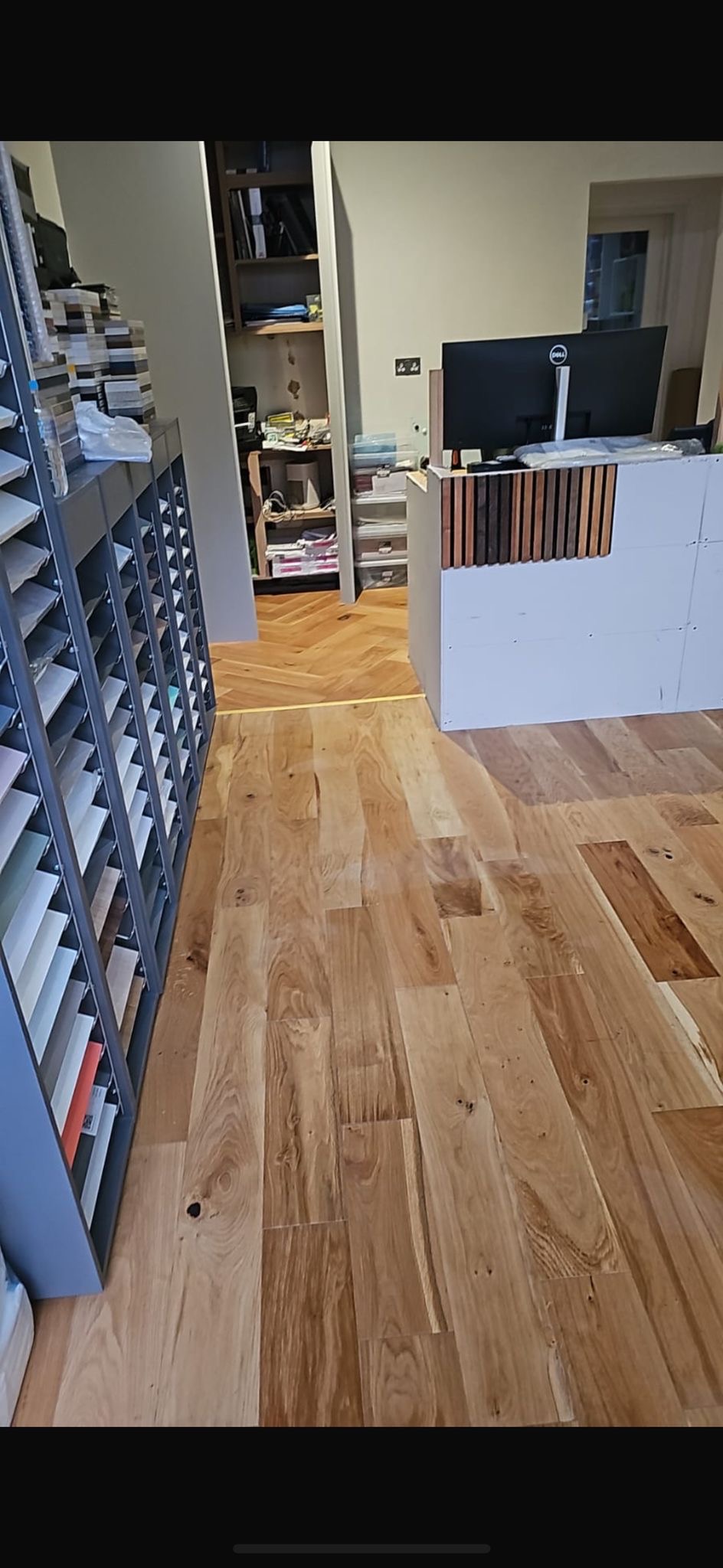 Oak flooring running past shelving towards a desk.